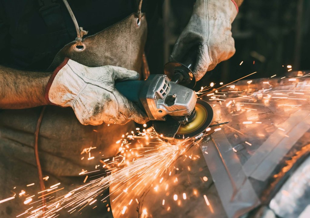 Hands of metalworker grinding copper in forge workshop